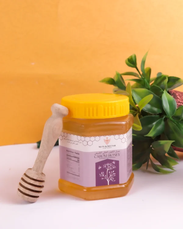Closed jar of Caroom Ajwain Honey with wooden honey dipper – Nuts & Nectar Pakistan